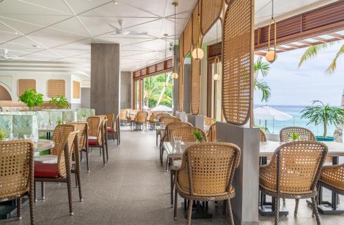 a dining room with tables and chairs and the ocean at Henann Premier Coast Resort in Panglao