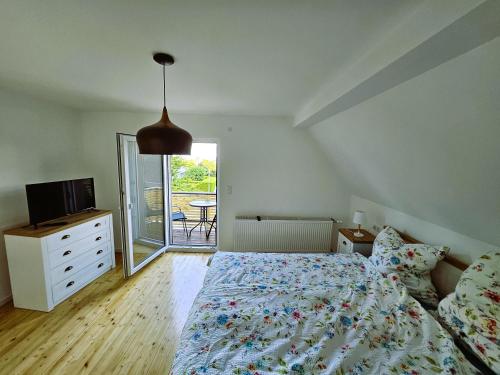 a bedroom with a bed and a television and a balcony at Maison Robichon in Frankweiler