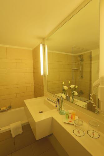 a bathroom with a sink and a mirror and a tub at Prima Galil Tiberias Hotel in Tiberias