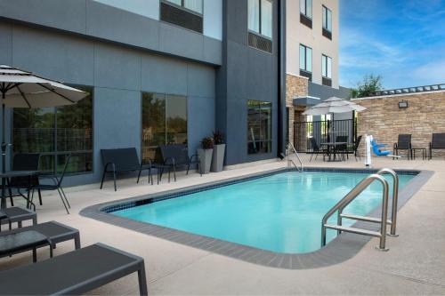 a swimming pool with tables and chairs next to a building at Fairfield Inn & Suites by Marriott Houston Pasadena in Pasadena