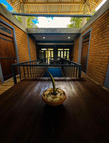 a plant in a bowl sitting on a wooden table at The Lotus Villa Sigiriya in Sigiriya
