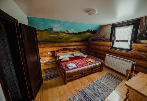 a bedroom with a bed and a painting on the wall at Casa din Valea Bucovinei in Valea Moldovei