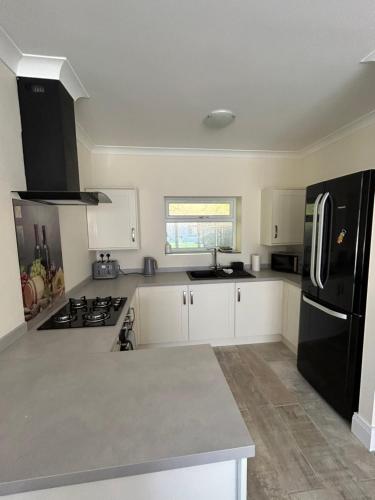 a kitchen with white cabinets and a black refrigerator at Sharpley Hall Garden Studio in Durham
