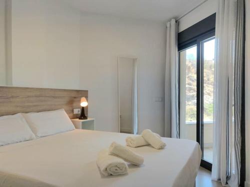 マラガにある1º Línea de playa con piscina panorámica & parkingのタオルが敷かれた白いベッドのある寝室