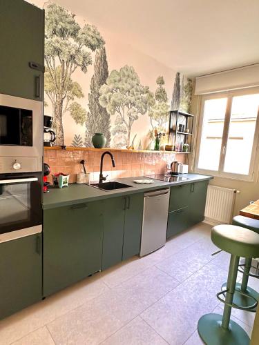 une cuisine avec des armoires vertes et un évier dans l'établissement Le 101 appartement dans charmant village parking facile, à Montville
