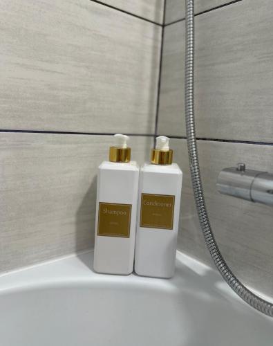 two white bottles ofodorizers sitting on top of a bath tub at Alma House in Deva