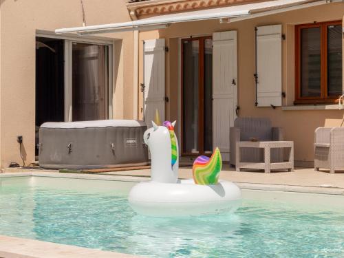 un cygne gonflable dans l'eau d'une piscine dans l'établissement Villa Piscine 20 min de Toulouse, à Fontenilles