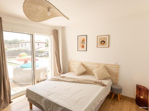 une chambre avec un lit et une grande fenêtre dans l'établissement Villa Piscine 20 min de Toulouse, à Fontenilles