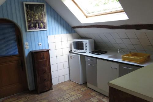 une cuisine avec une fenêtre et un four micro-ondes sur un comptoir dans l'établissement logement a l'étage d'une longère Normande, à Saint-Wandrille-Rançon