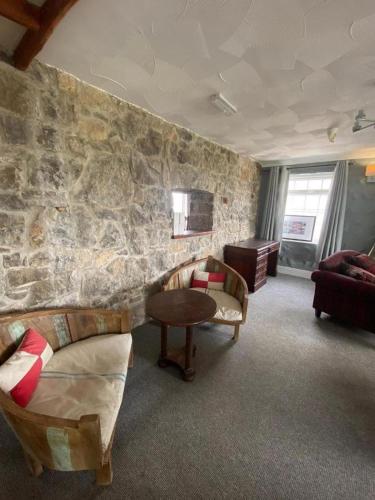 a room with a stone wall with two beds and a table at Ty Dderw Country Inn in Moelfre