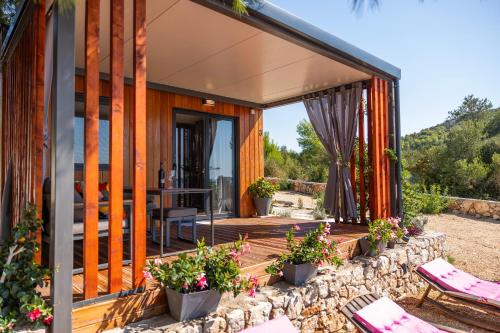 a house with a stone wall and a patio at Paradisum sub sole in Tisno
