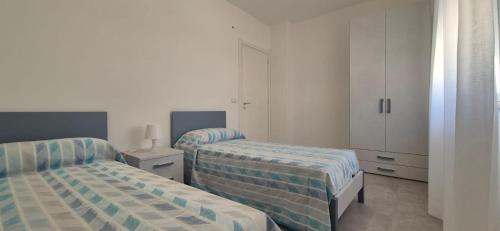 sypialnia z 2 łóżkami i białą szafką w obiekcie Le Dimore di Donato w mieście Torre San Giovanni Ugento