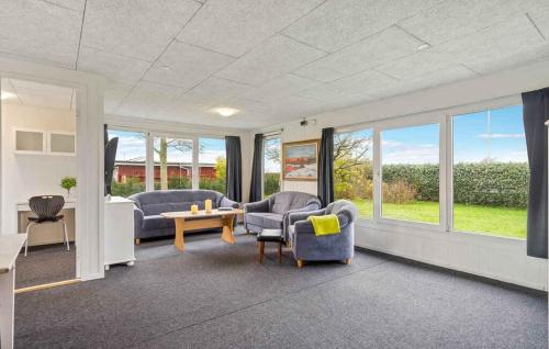 a living room with two chairs and a table and windows at Lovely Summer House By Venø Bay in Vinderup