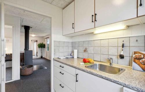 a kitchen with white cabinets and a sink at Lovely Summer House By Venø Bay in Vinderup