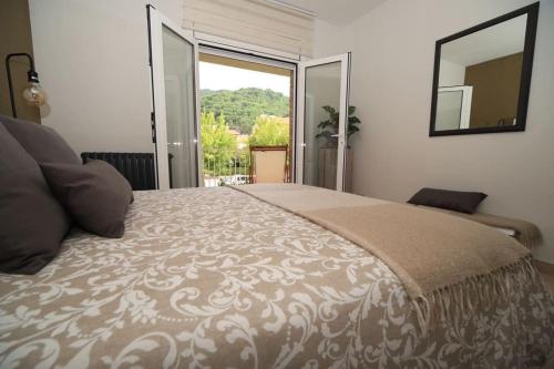 Un dormitorio con una cama grande con una ventana grande. en Magnífic dúplex amb doble terrassa, en Sant Joan de les Abadesses