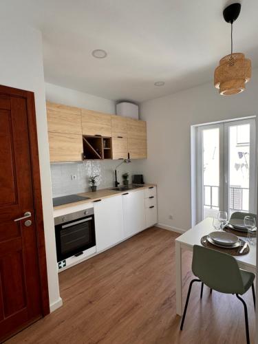 a kitchen with white cabinets and a table and a dining room at Salty Apartments in Nazaré