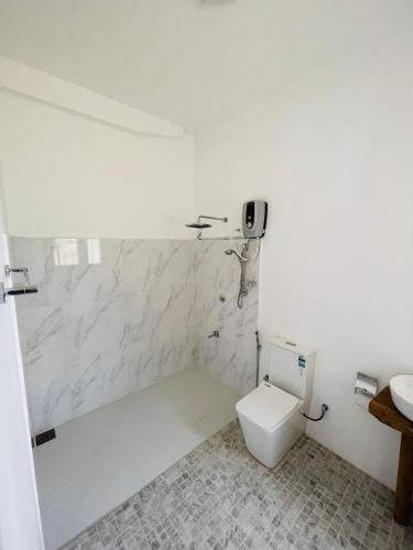 a white bathroom with a toilet and a sink at The Lotus Villa Sigiriya in Sigiriya