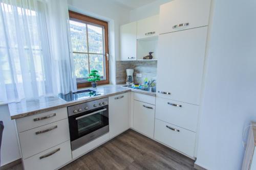 a white kitchen with white cabinets and a window at Huberhof 5 by Alpenidyll Apartments in Rohrmoos