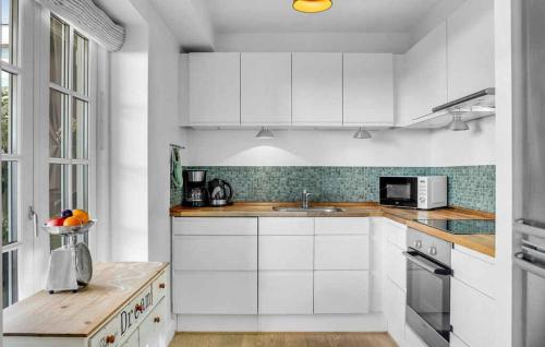 a white kitchen with white cabinets and a sink at Modern And Luxurious Holiday Apartment In Rørvig in Rørvig