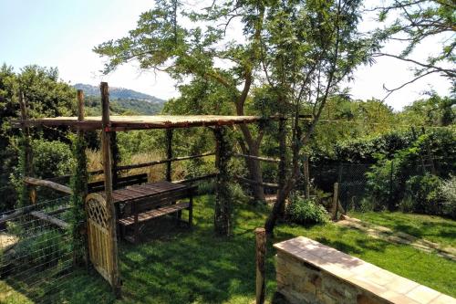 a wooden bench in a yard with a fence at PODERE TORRICELLE 69B Pancole Gr, seaview infinity pool, jacuzzi, sauna, exclusive villa with 2 bedrooms for 4 - If you total 5 or 6 people there is an independent suite in main villa with private ensuite bathroom, kitchenette and garden dining area in Pancole