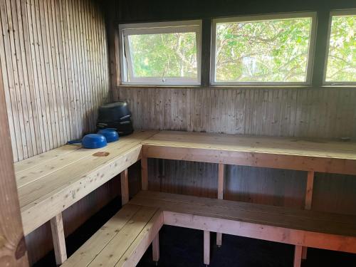 a wooden bench in a room with two windows at The paradise by the beach in Långviken