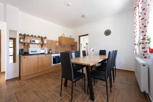 a kitchen and dining room with a wooden table and chairs at Fehér Galamb Vendégház in Tolmacs