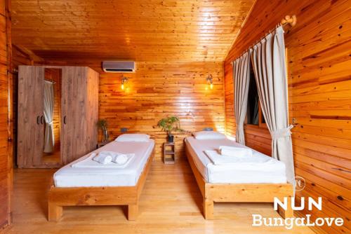 two beds in a room with wooden walls at Çıralı Nun Bungalove in Cıralı