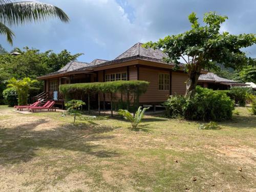 a house with a tree and chairs in front of it at Heliconia Grove in Baie Sainte Anne