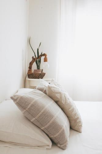 a white bed with two pillows on it at Vila Vale Guest House - Surf & Yoga in Charneca