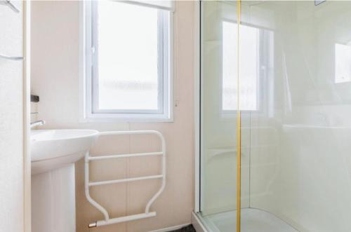 a bathroom with a glass shower and a sink at Fistral fields 2 in Cubert