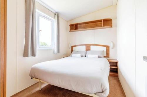 a bedroom with a white bed and a window at Fistral fields 2 in Cubert