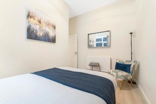 a white bedroom with a bed and a chair at Modern Two Bedroom Central Flat in Weston-super-Mare