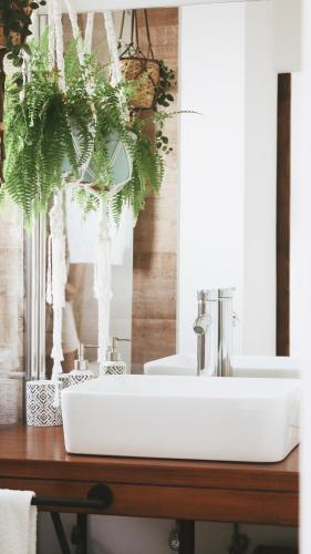 a bathroom sink on a wooden counter with a plant at Vila Vale Guest House - Surf & Yoga in Charneca