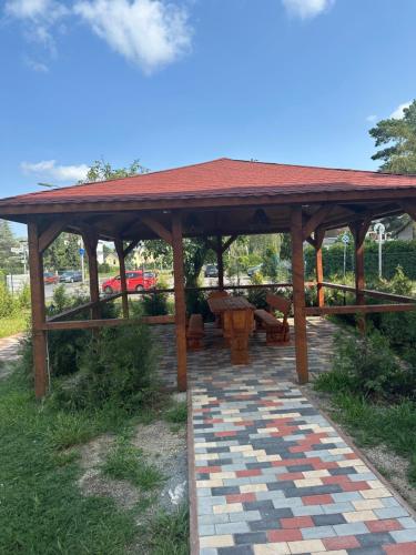 a wooden gazebo with a table and benches at Hotel Pirol in Berlin