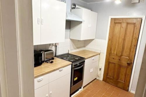 a small kitchen with a stove and white cabinets at Two Bedroom Flat Close to Newcastle City Centre in Elswick