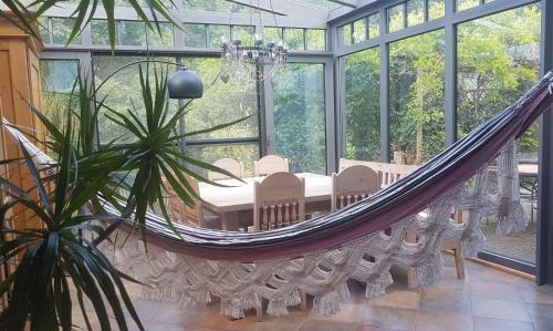 a hammock in a conservatory with a room with windows at Ferienhaus Glücksnest in Hetzerath