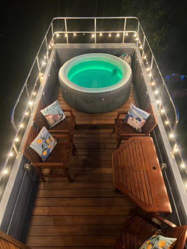a bath tub in a deck with chairs and a table at Delightful 2 Bed Double Decker Bus with Hot Tub in Uckfield