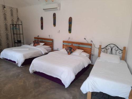 a room with three beds with white sheets at Boulevard Inn Mt Meru in Arusha