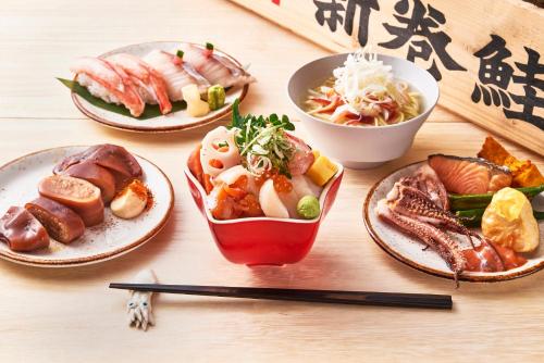 a wooden table with plates of food and chopsticks at OMO5 Hakodate by Hoshino Resorts in Hakodate