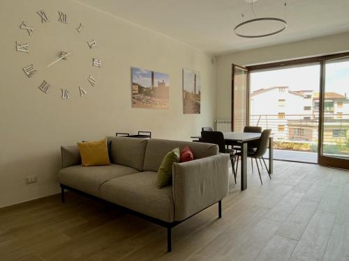 a living room with a couch and a clock on the wall at Sotto le Mura, appartamento Mosaico in Siena