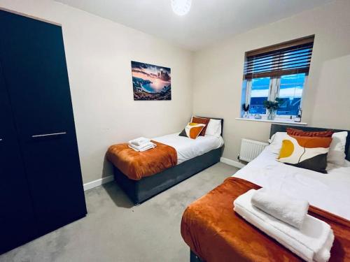 a bedroom with two beds and a window at Spacious 4 Bedroom, 3 Bath House by Jesswood Properties Contractors, Business and Leisure with Free Parking and WIFI in Peterborough