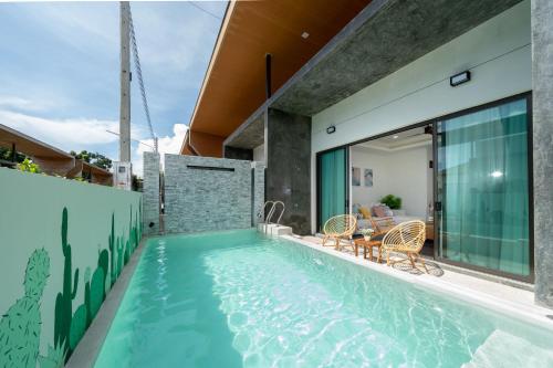 an indoor swimming pool with chairs and a house at Stylish Pool Villa in Chalong-Phuket-2 Bedroom in Ban Suan