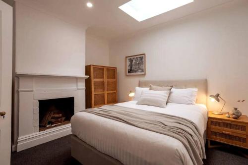 ein Schlafzimmer mit großem Bett und Kamin in der Unterkunft Tamara Cottage Historic Warmth in Hobart