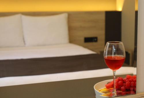 a glass of wine sitting on a table with a bowl of fruit at Grand Faik Hotel in Çeşme