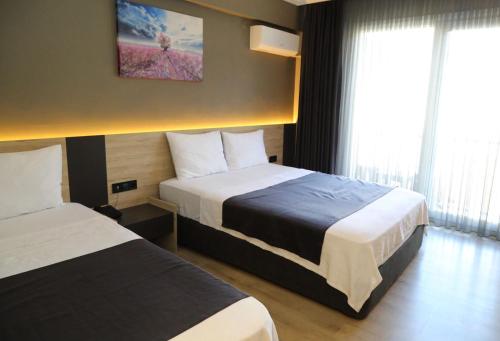 a hotel room with two beds and two windows at Grand Faik Hotel in Cesme