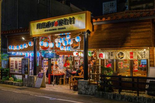 a restaurant with people sitting in front of it at night at 国際通り徒歩1分 駐車場2台 最大11名 空港車で10分 周辺には飲食店多数の那覇エリア さくらや国際通り in Naha