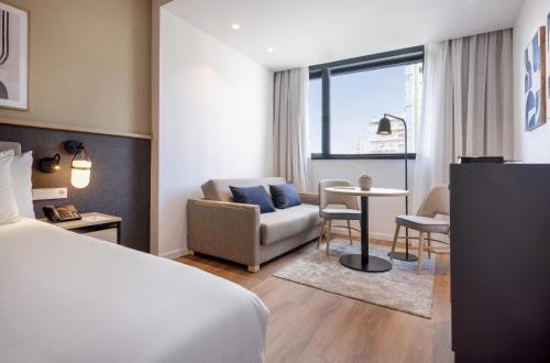 a hotel room with a bed and a couch at Hotel Málaga Alameda Centro Affiliated by Meliá in Málaga