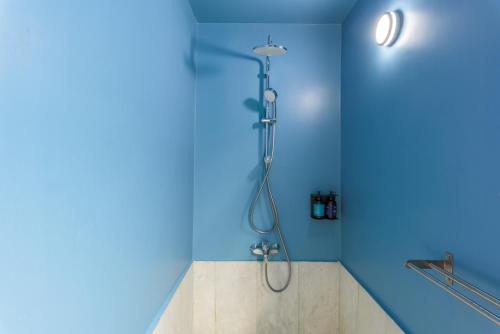 a shower in a blue bathroom with a shower head at SAYA La Villa in Mar Mikhael in Beirut