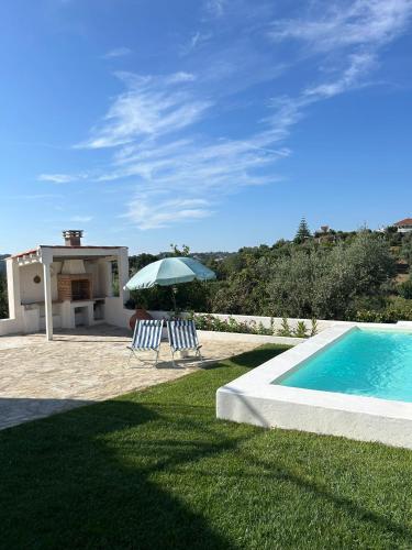 two chairs and an umbrella next to a swimming pool at A casa dos avós in Abrantes