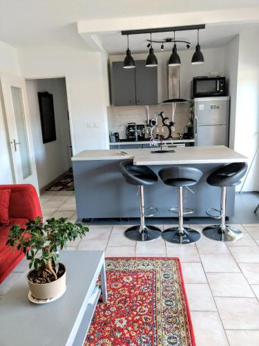 une cuisine avec un comptoir et des tabourets dans une pièce dans l'établissement Résidence Les Jardins de la Mer, à Sainte-Maxime